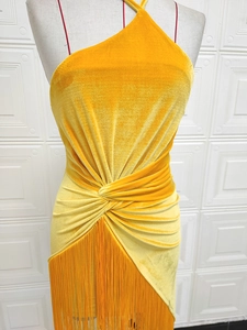 Détail d'une robe en velours jaune avec licou et ourlet asymétrique à franges