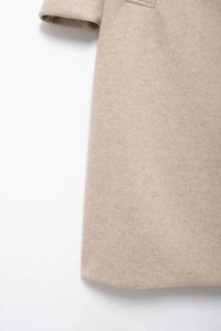 Gros plan sur la texture du manteau en laine avoine avec des finitions de couture haut de gamme