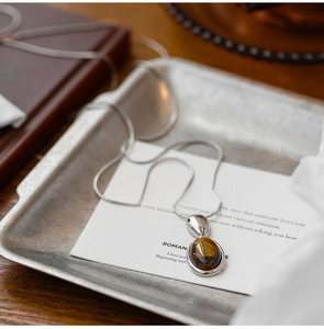 Detailed view of silver tiger eye stone pendant necklace on a minimalist snake chain