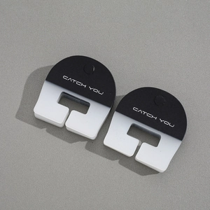 Detail of semi-circular black and white hair clips with CATCH YOU artistic lettering
