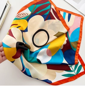 Detail of silk satin square scarf with abstract floral print and vibrant orange border