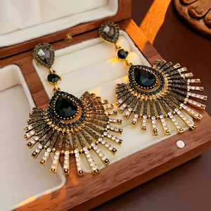 Macro view of vintage gold earrings with black teardrop crystals on beige velvet pad