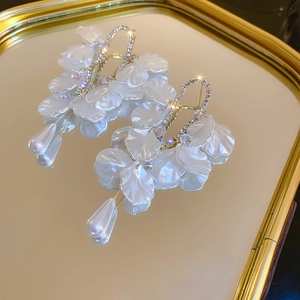 Gros plan de boucles d'oreilles fleurs en perles et cristaux sur un plateau miroir doré