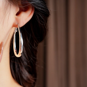 Close-up of minimalist silver geometric U-shaped hoop earrings worn by a model