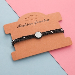 Close-up of black braided cord bracelet with silver metal beads on a display card