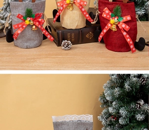 Close-up of three festive drawstring gift bags with pine needles and bells on wood