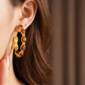 Vintage C-shaped tiger eye stone and pearl gold-plated earrings worn by a model
