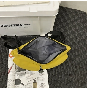Close-up of yellow nylon messenger bag showing black zipper and grey interior lining