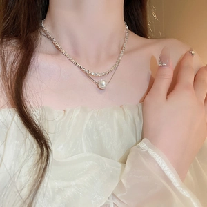 Detail of double-layer necklace featuring crushed silver chain and white pearl pendant