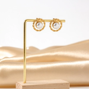 Elegant gold twisted texture round pearl stud earrings displayed on a gold stand
