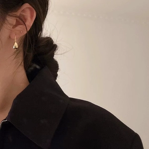 Close-up of golden mushroom teardrop earrings worn by a model with a minimalist style