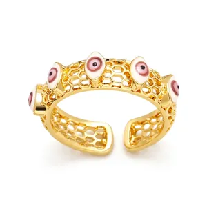Détail d'une bague dorée ajourée avec motifs œil protecteur en émail rose et blanc