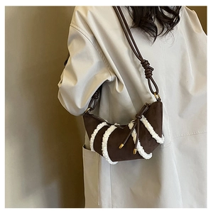 Detailed close-up of retro brown suede crescent bag with white faux fur trim decoration