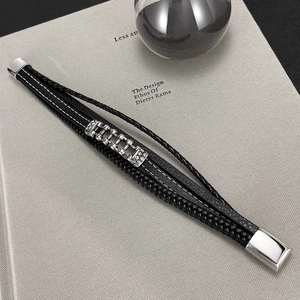 Detailed view of handmade braided black leather bracelet with magnetic clasp on a book