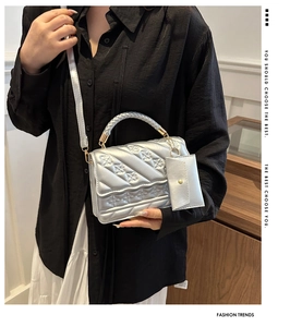 Detail of silver embossed crossbody bag with braided handle and mini coin purse charm