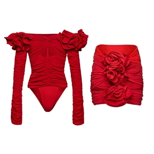 Detailed view of bright red two-piece outfit featuring 3D rose decor and pleated fabric