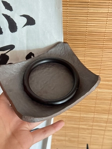Gros plan d'un bracelet en bois noir lisse sur une assiette en céramique rustique