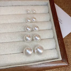 Elegant 5-pair set of minimalist white round pearl earrings in various sizes on velvet