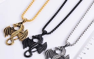 Detailed close-up of dragon pendants in gold, black, and silver with bead chains