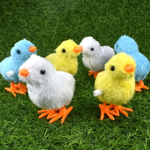 Wind-up plush jumping chicken toys in yellow blue and white on green grass background