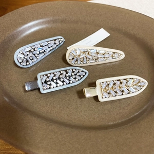 Close-up of teardrop and arched zircon hair clips in light blue and cream beige colors