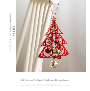 Detail of red Christmas tree hanging ornament with small golden bells on a fence