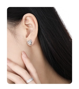 Close-up of a model wearing heart stud earrings and a textured silver ring