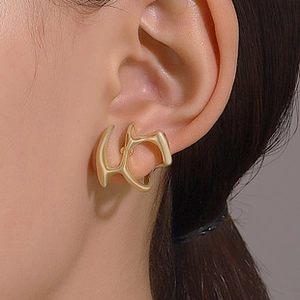 Close-up of matte gold abstract geometric ear cuff worn by a model in a side view