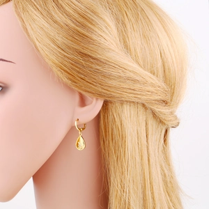 Close-up of a model wearing golden starburst teardrop earrings with crystals