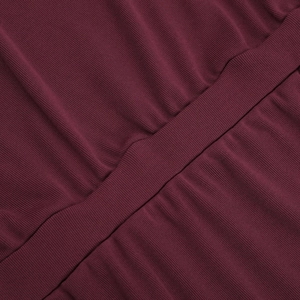 Detailed macro view of burgundy ribbed knit fabric with precise stitching on dress
