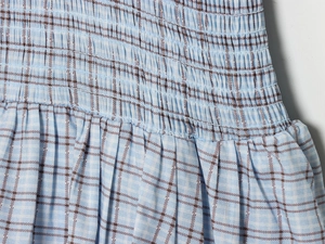 Detail of blue and brown plaid fabric with elastic smocking and pleated texture