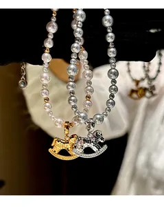 Macro detail of gold and silver horse charms on high-luster white pearl necklaces