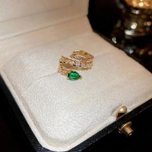 Golden snake ring with green teardrop zircon and pavé crystals on a jewelry box