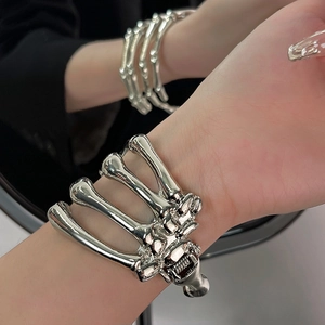 Detailed close-up of a silver skull hand skeletal metal bracelet with adjustable cuff