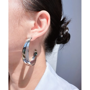 Polished silver teardrop C-shape hoop earrings worn by a model in natural light