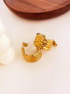 Detail goldene C-Ohrstecker mit unregelmäßiger Lavastruktur auf minimalistischer Basis