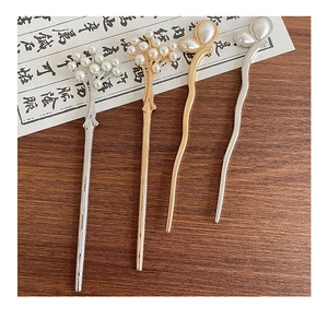 Detailed view of four elegant gold and silver hairpins with pearls on a vintage background