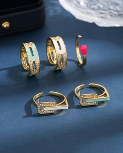Detail shot of five gold jewelry pieces with colorful enamel and inset clear crystals