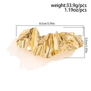 Detailed macro view of gold liquid metal hair clip with irregular wrinkled surface texture