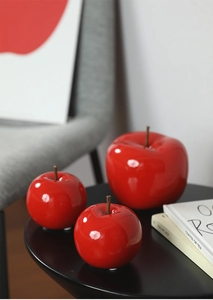 Détails rapprochés de pommes décoratives en céramique rouge brillant sur table moderne