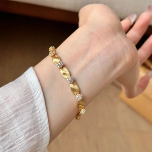 Gold brushed leaf bracelet with sparkling diamond flower accents worn by a model