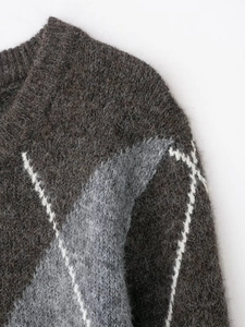 Vue rapprochée d'un pull en maille avec col en V, texture douce et motifs géométriques
