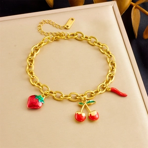 Detail of gold chain bracelet with strawberry, cherry, and chili enamel charms