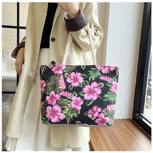 Detailed shot of large floral canvas tote bag with white rope handle carried by a model