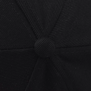 Macro detail of top button and fine stitching on a black cotton twill baseball cap