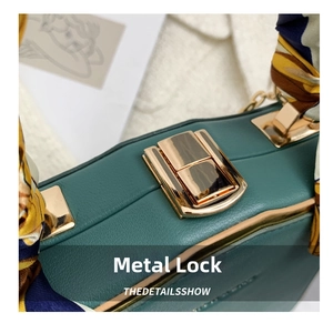 Detailed close-up of dark green leather handbag with gold metal clasp and silk scarf handle