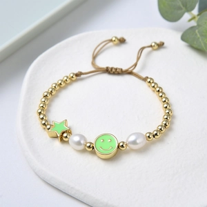 Detail of adjustable beaded bracelet with green enamel star, smiley face and freshwater pearls
