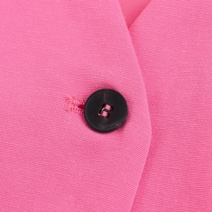 Gros plan du gilet rose avec bouton noir et texture de tissu de haute qualité