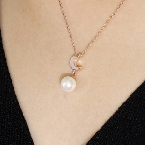Close-up of rose gold moon pendant with a white pearl on a delicate 925 silver chain