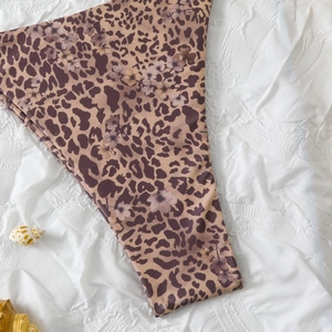 Detailed view of leopard and floral print bikini bottom on white textured background